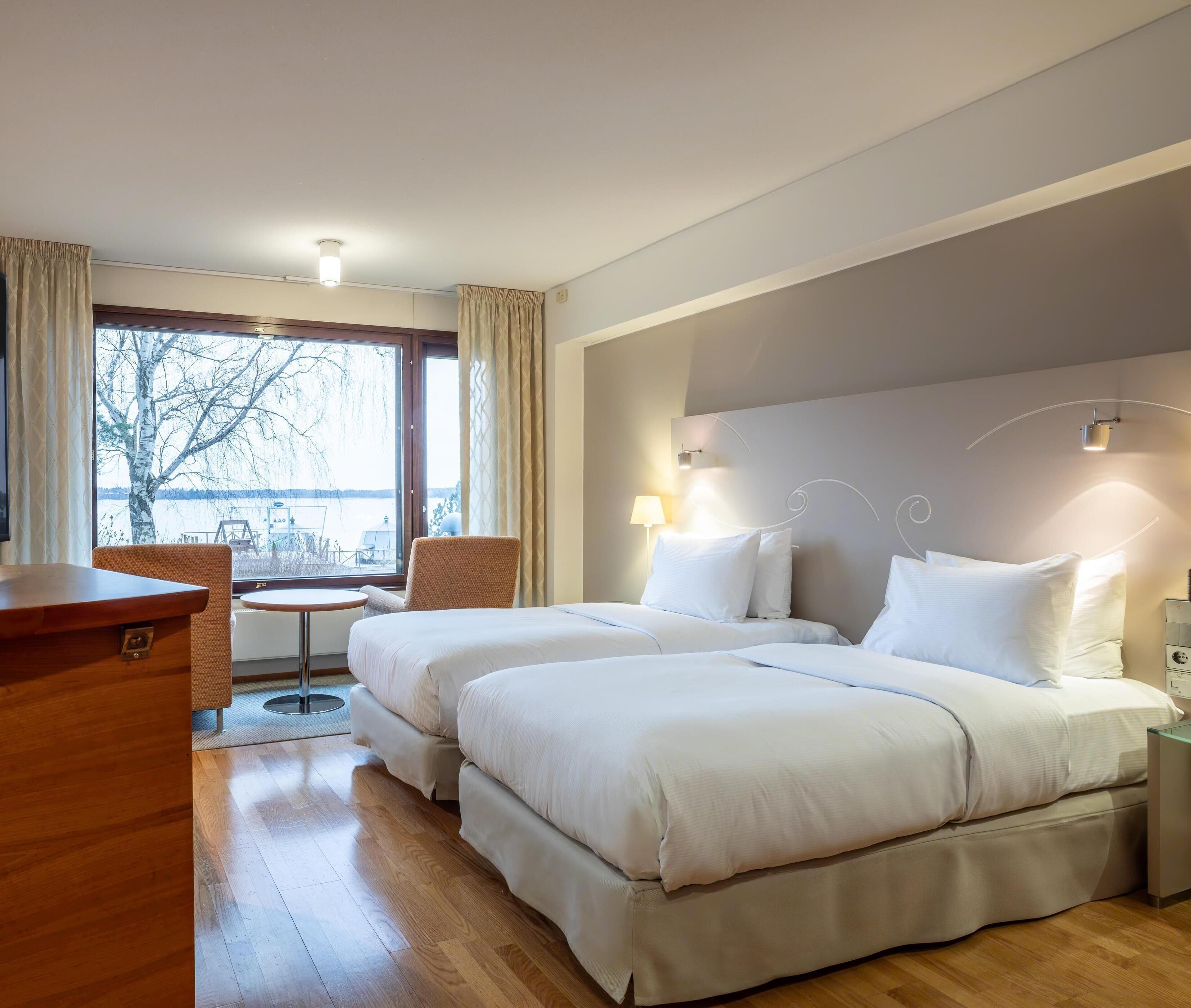 Camera d'albergo con due letti, una scrivania, una sedia e vista su un corpo d'acqua.