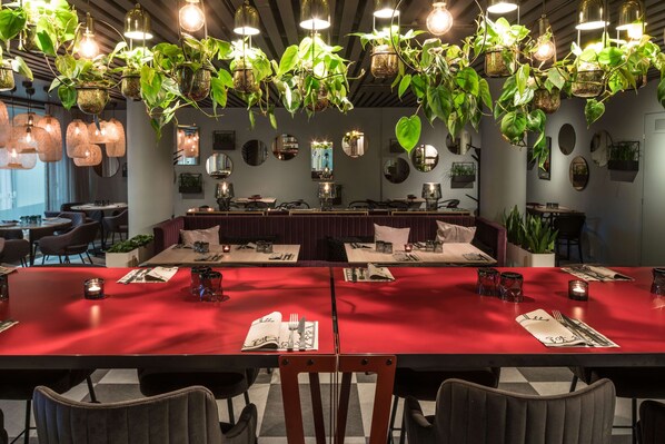 Un restaurante con mantel rojo, plantas colgantes y una decoración interior moderna.