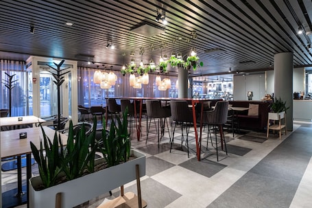 A modern interior with a checkered floor, bar seating, and hanging plants.