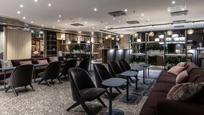 Un espace de détente moderne, doté de canapés, de fauteuils et de tables, avec une palette de couleurs neutres et un design contemporain.