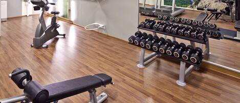 A gym with exercise equipment, including a treadmill, elliptical, and dumbbells.