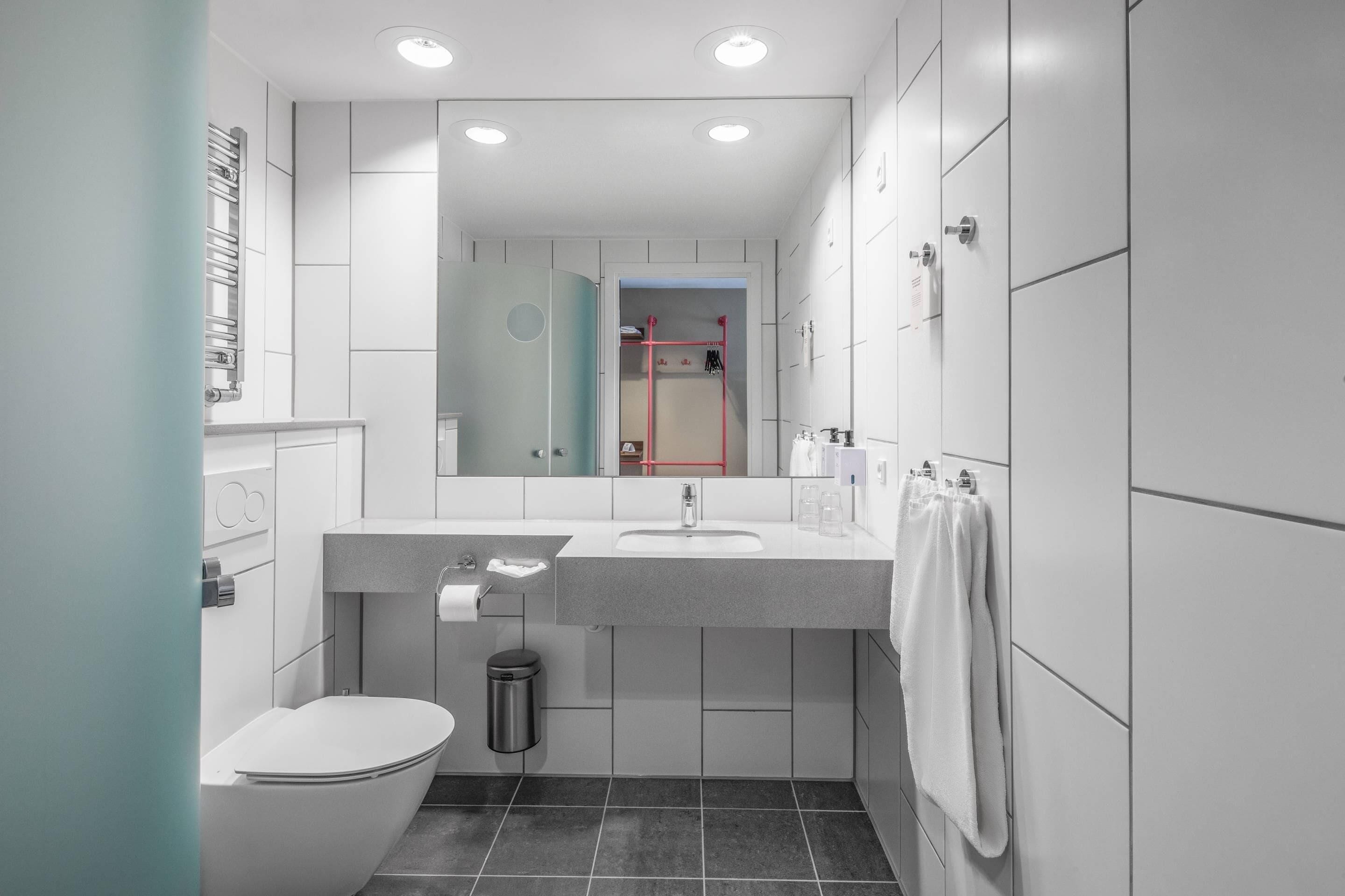 Un baño moderno con inodoro, lavamanos y espejo.