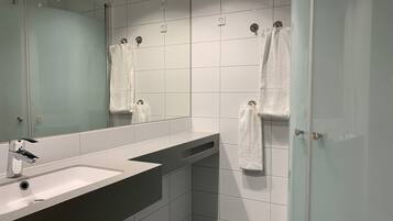 A modern bathroom with a large mirror, a sink, and a shower area.