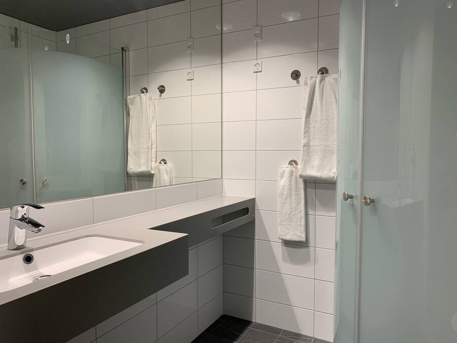 A modern bathroom with a large mirror, a sink, and a shower area.