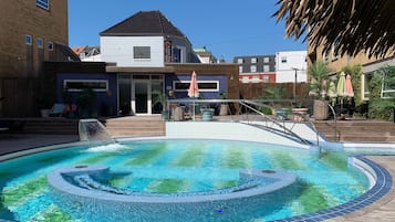 En swimmingpool med jacuzzi, omgivet af en træterrasse og plantekasser.