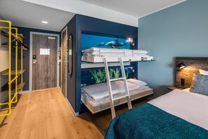 Una cama litera con escalera, un escritorio pequeño y una mesita de noche con lámpara.