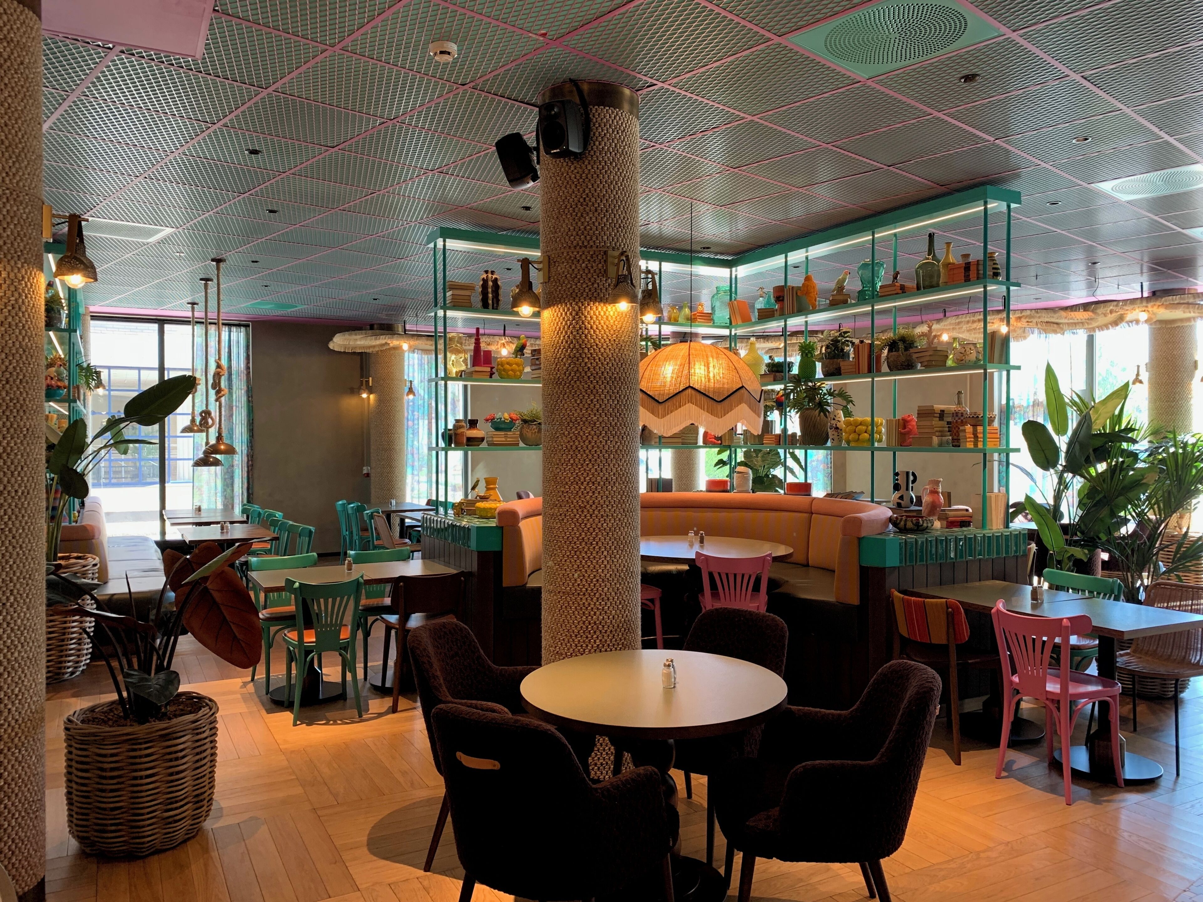 Un café acogedor con una zona de estar central, una barra con estantes llenos de botellas y un techo con diseño.