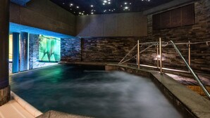 A spa area with a stone wall, a pool, and a staircase. - Quality Hotel The Reef (Frederikshavn)