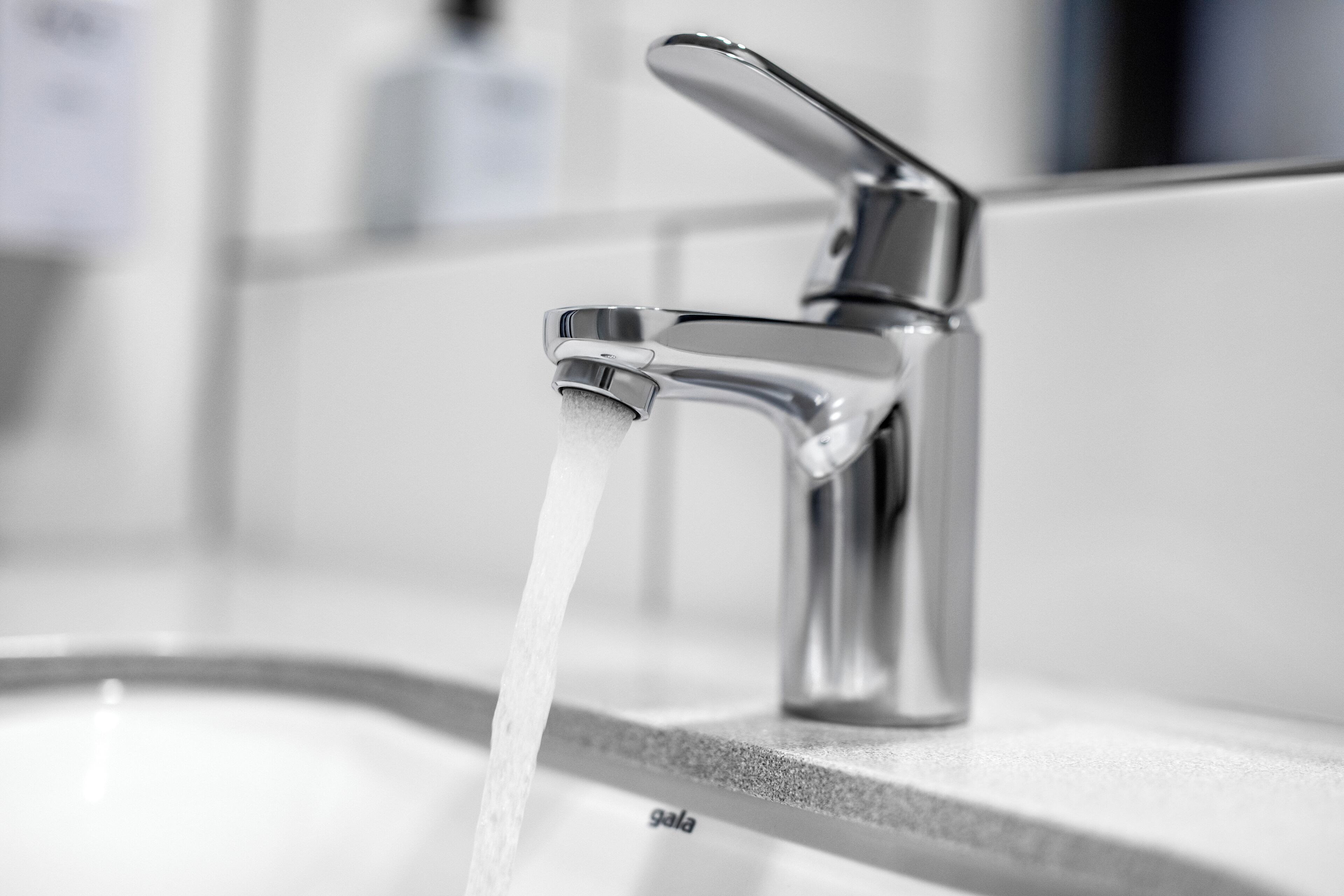 Een moderne badkamer met een chromen kraan en stromend water.