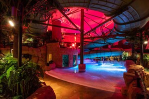 Una piscina techada, una piscina al aire libre, sombrillas