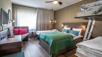 A hotel room with a bed, a desk, a chair, a bunk bed, and a ceiling fan.
