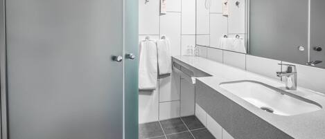 Un baño moderno con dos lavamanos, un espejo grande y una puerta que da a otra habitación.