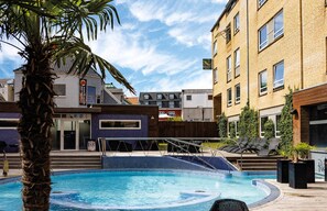 Una piscina techada, una piscina al aire libre, sombrillas