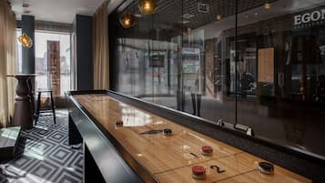 A shuffleboard table in a modern hotel lobby with a view of a restaurant in the background.