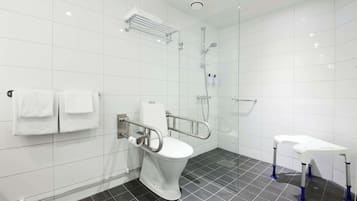 A modern bathroom with a white toilet, a shower, and a sink.