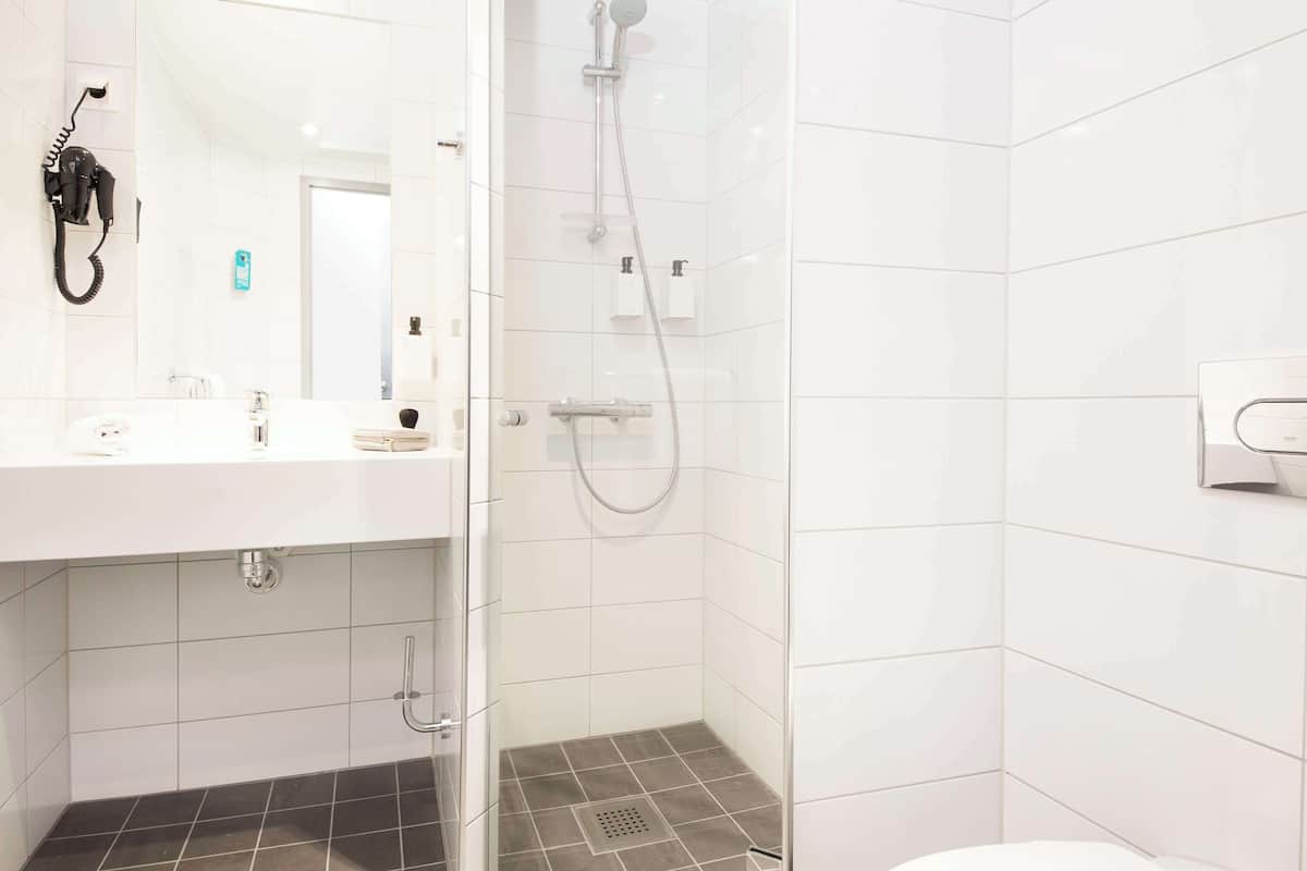 A modern bathroom with a glass shower enclosure, a white sink with a mirror, and a toilet.