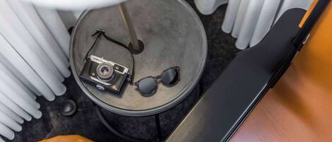 A round table with a camera, sunglasses, and a brown leather bag.