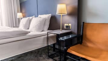 Ett hotellrum med en säng, två sänglampor, ett litet bord och en stol.