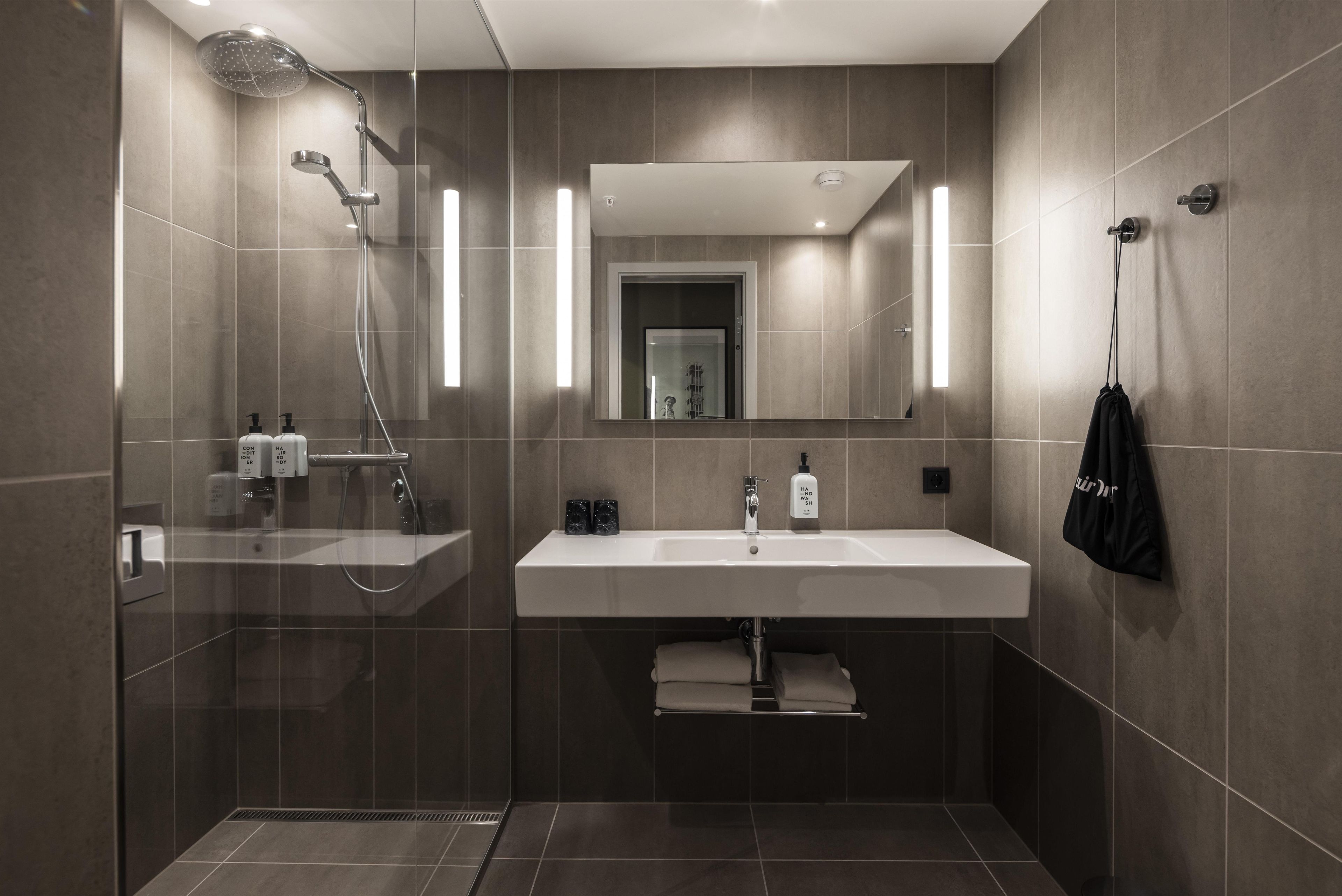 A modern bathroom with a shower, sink, and towel rack.