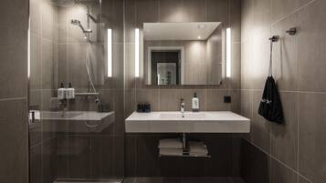 A modern bathroom with a shower, sink, and towel rack.