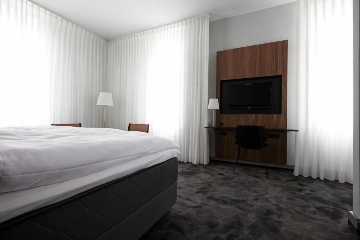 Een hotelkamer met een bed, een bureau met een televisie en een stoel.