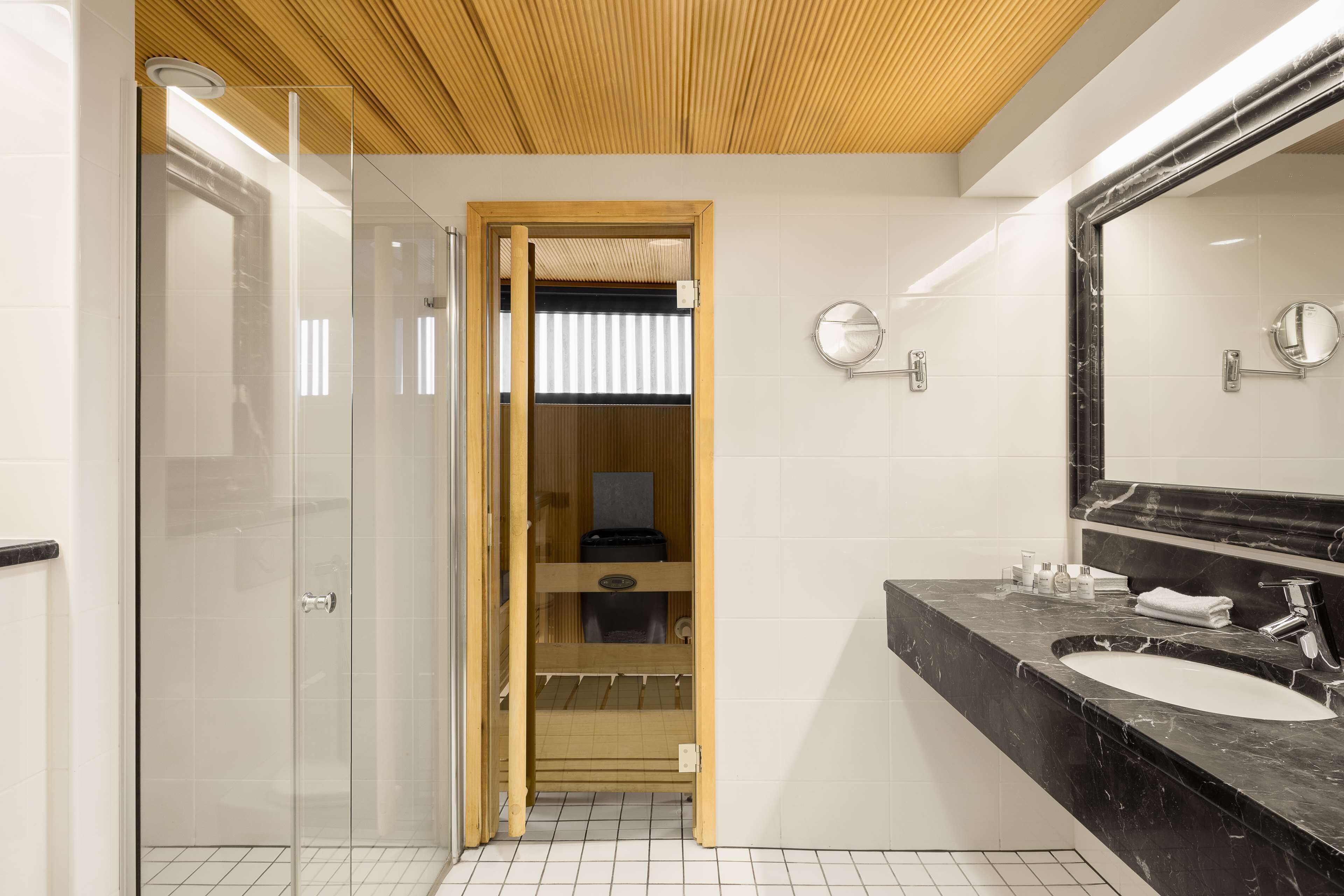 A modern bathroom with a glass shower enclosure, a wooden vanity, and a large mirror.