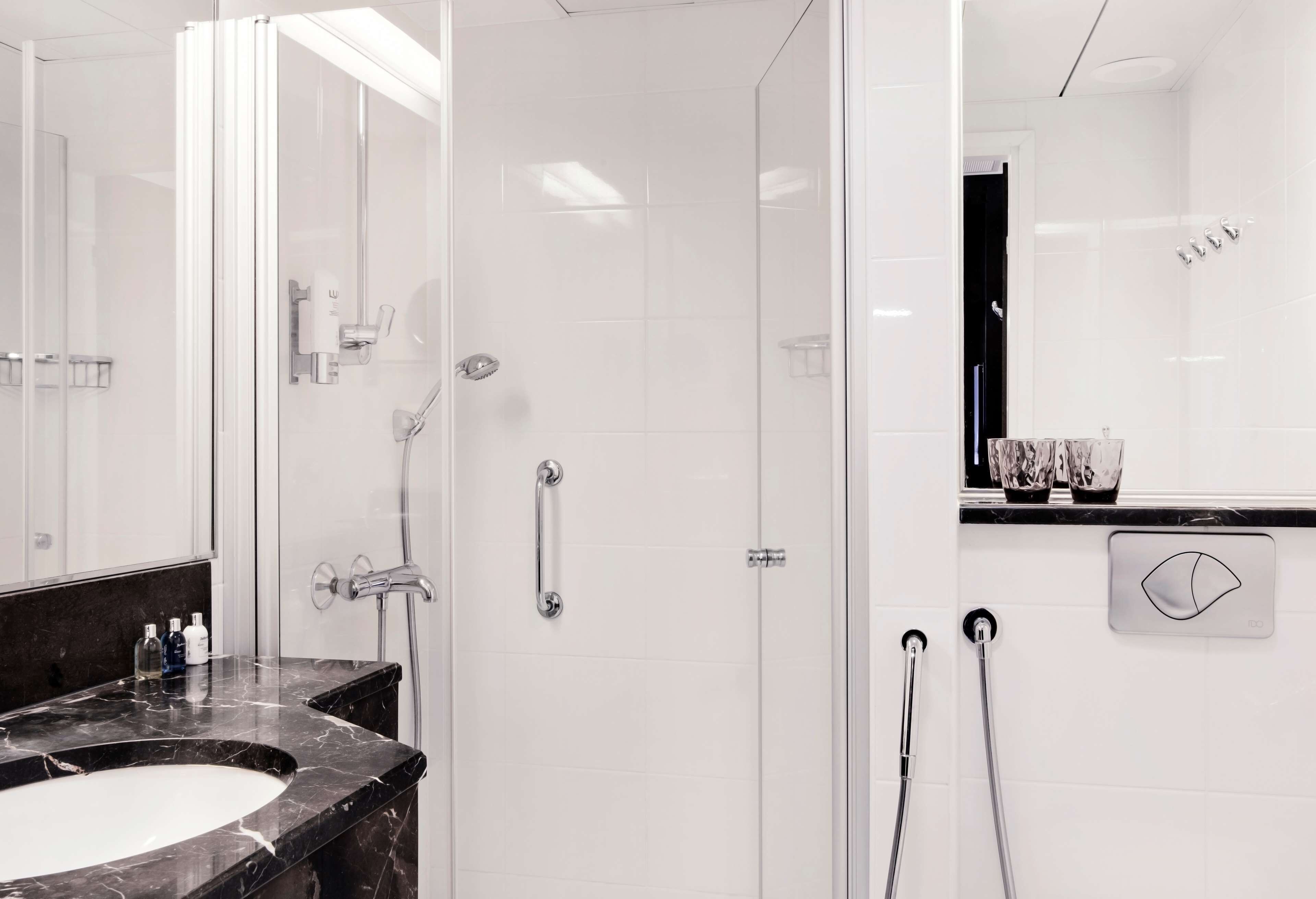 A modern bathroom with a glass-enclosed shower, a marble sink, and a vanity with a mirror.