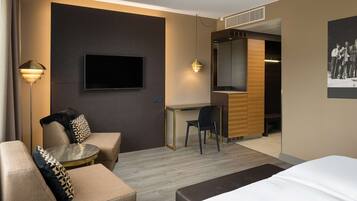 A modern hotel room with a bed, a sofa, a desk, and a chair.