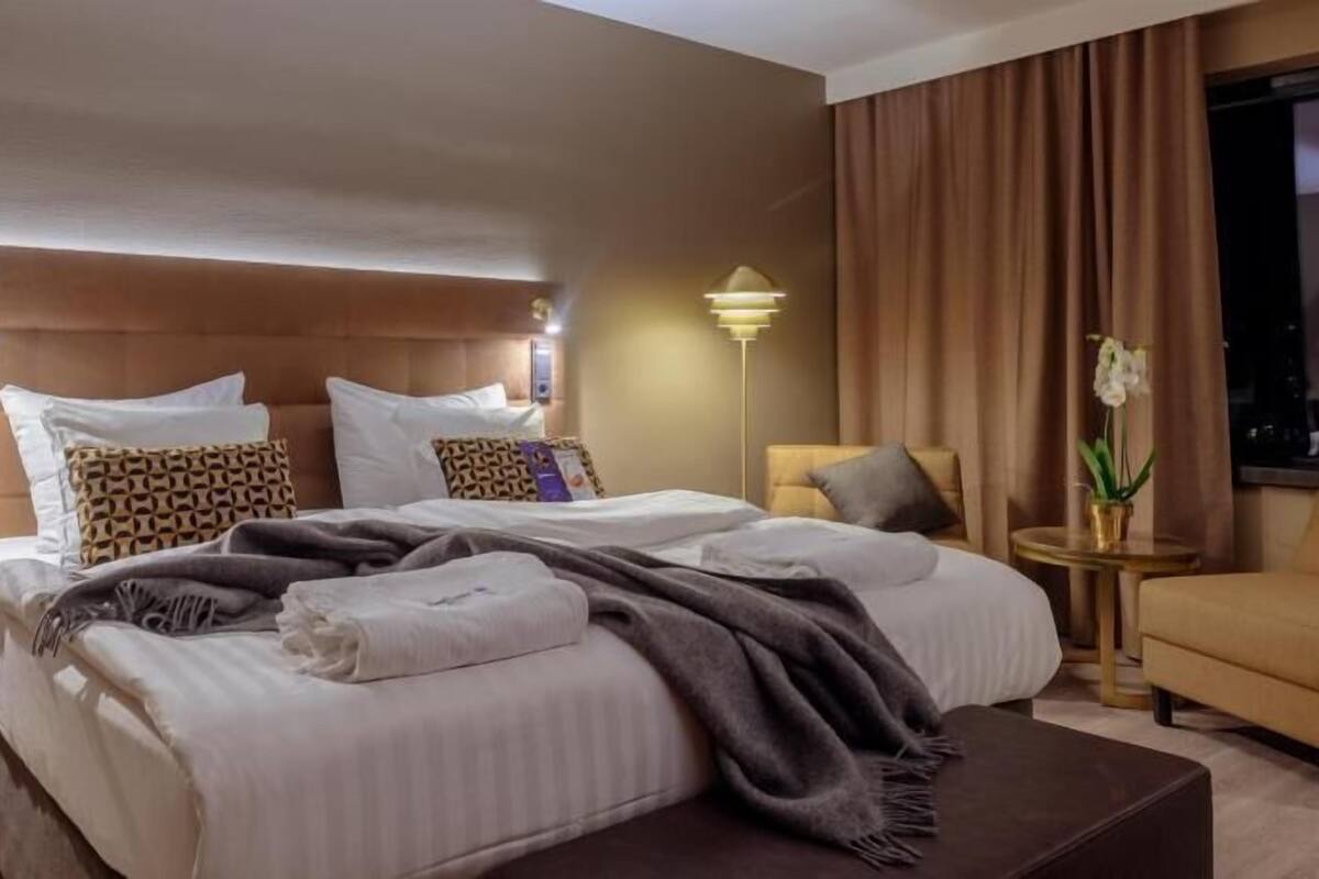 Ein Hotelzimmer mit einem großen Bett, Nachttischen, einem Sofa und einer Lampe.
