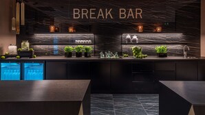 En stilfuld bar med en marmor bagplade, glashylder og en elegant sort bordplade.