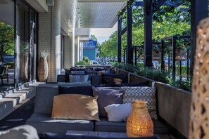 Relax in a comfortable outdoor seating area with sofas and chairs, surrounded by a low wall and ambient lanterns.