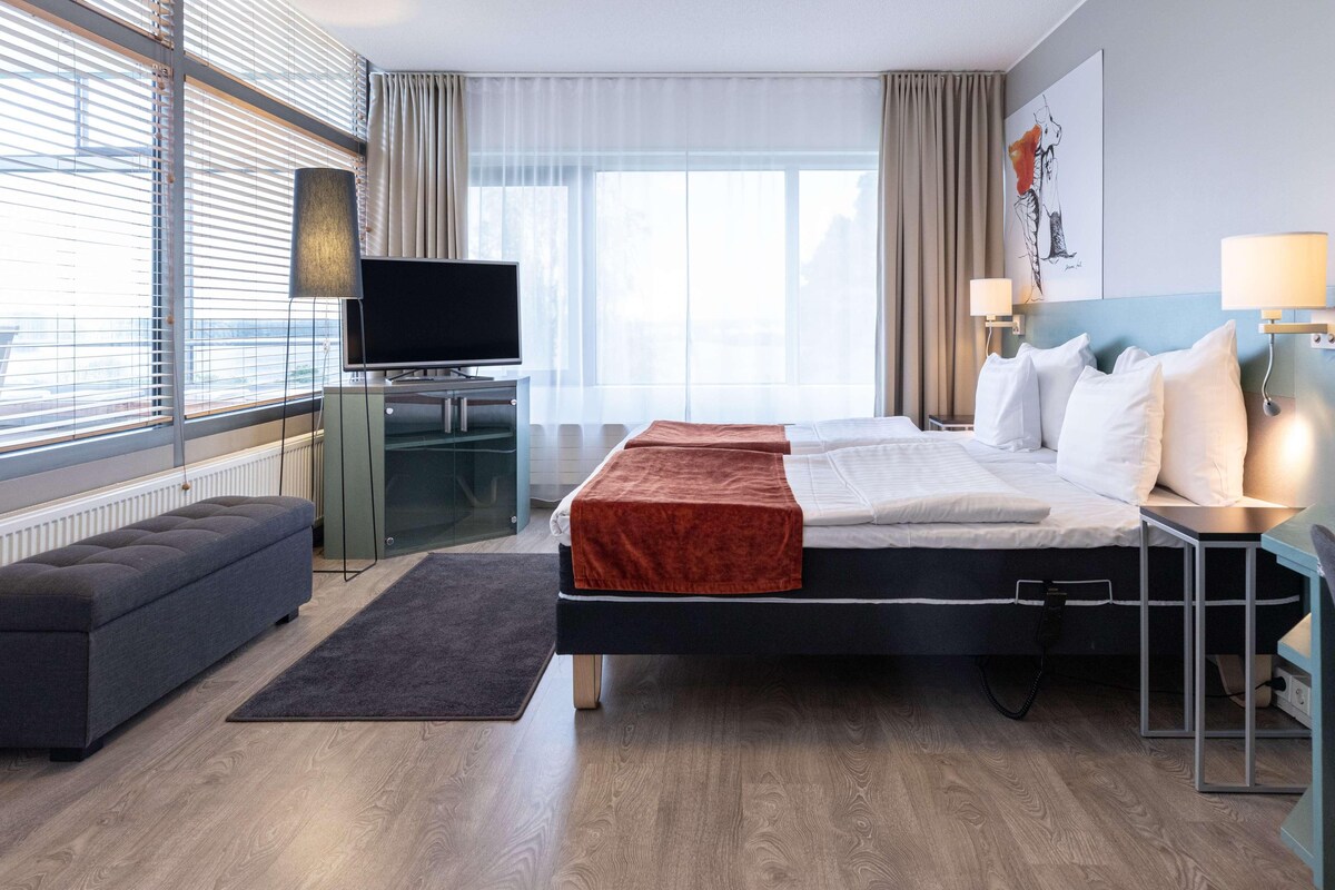 Una habitación de hotel con cama, televisor, escritorio y sofá.
