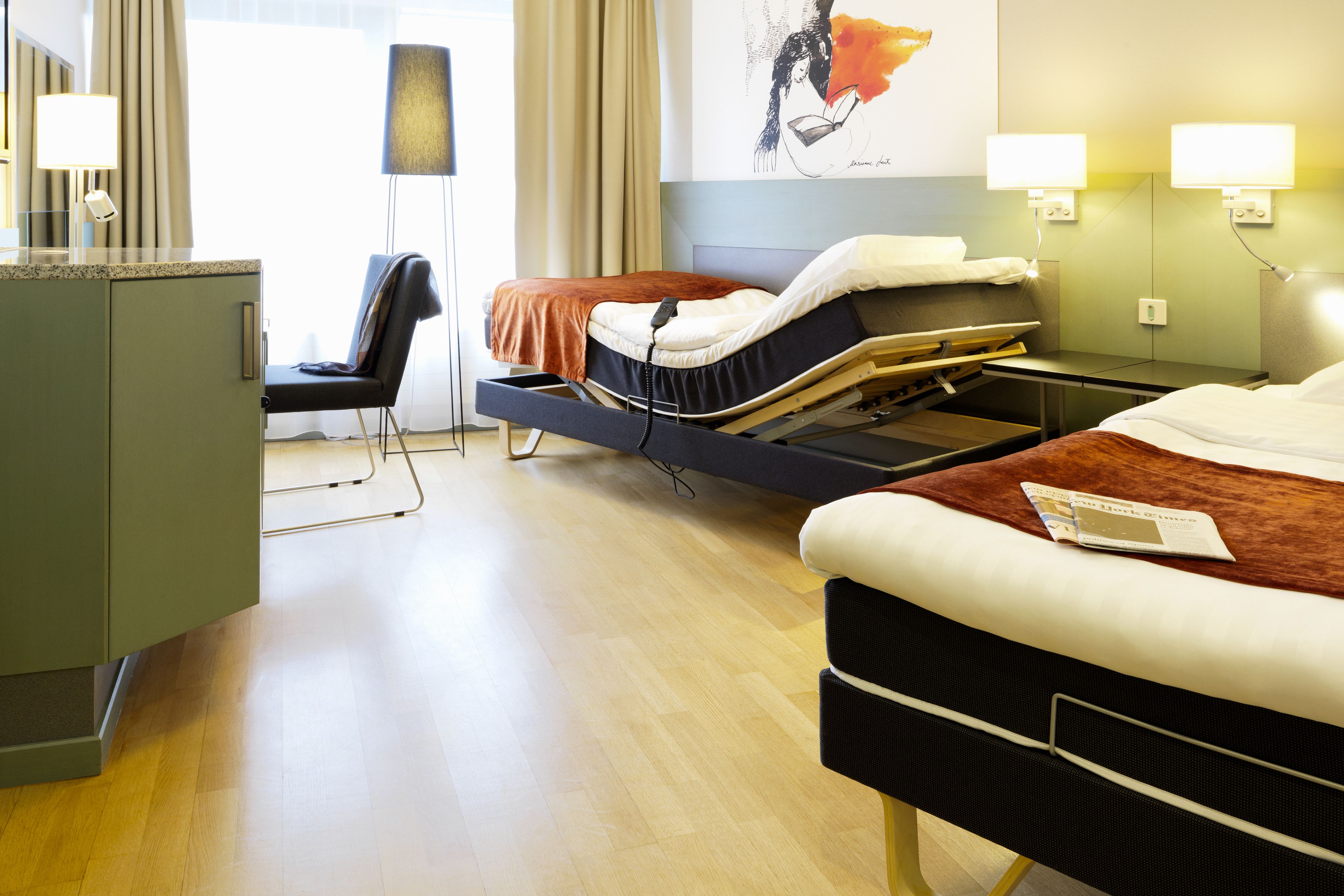 A hotel room with a bed, bedside table, and a desk with a chair.