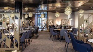 Un comedor moderno con mesas redondas, sillas oscuras y lámparas decorativas.