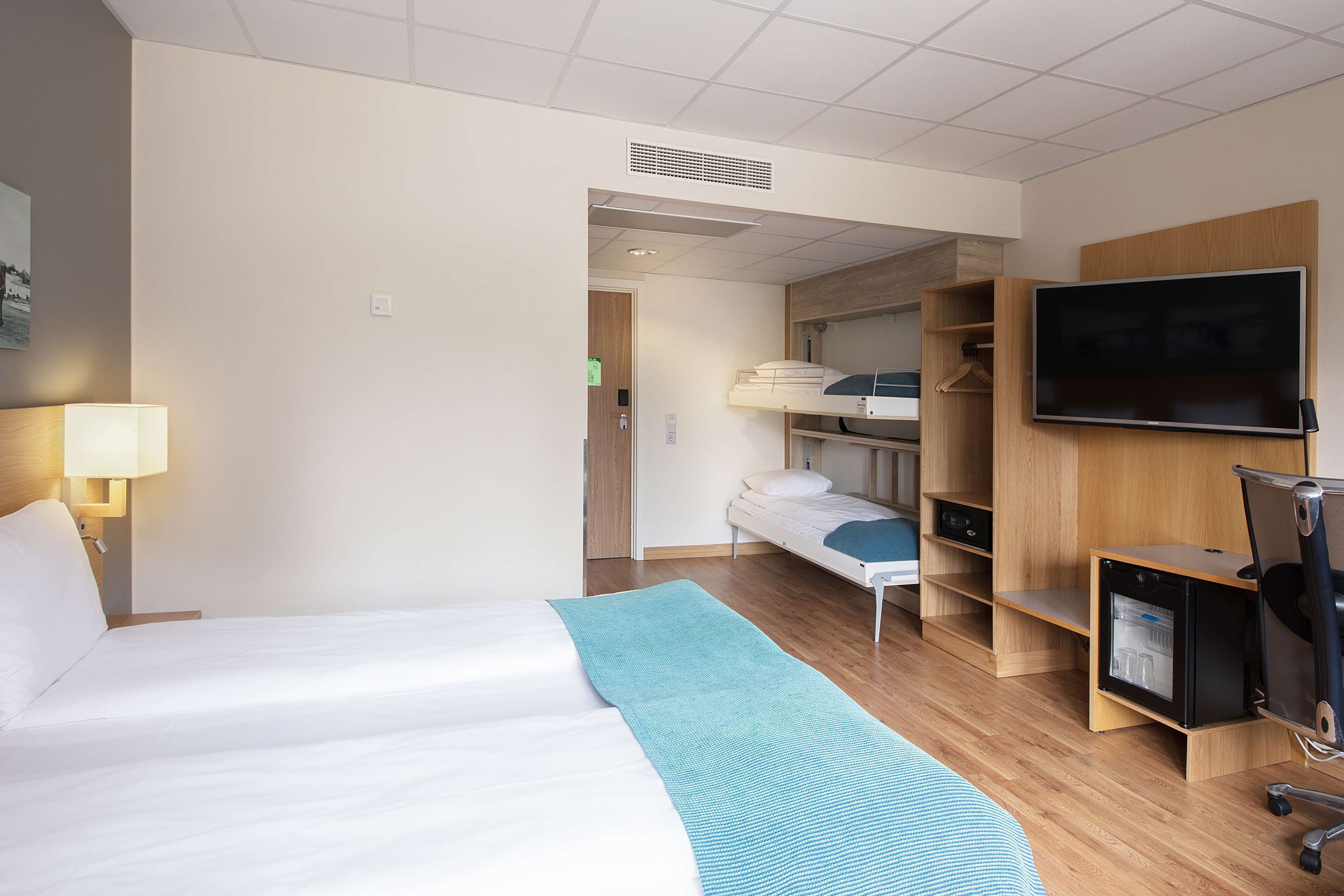 A hotel room with a bed, a TV, a desk, and a wardrobe.