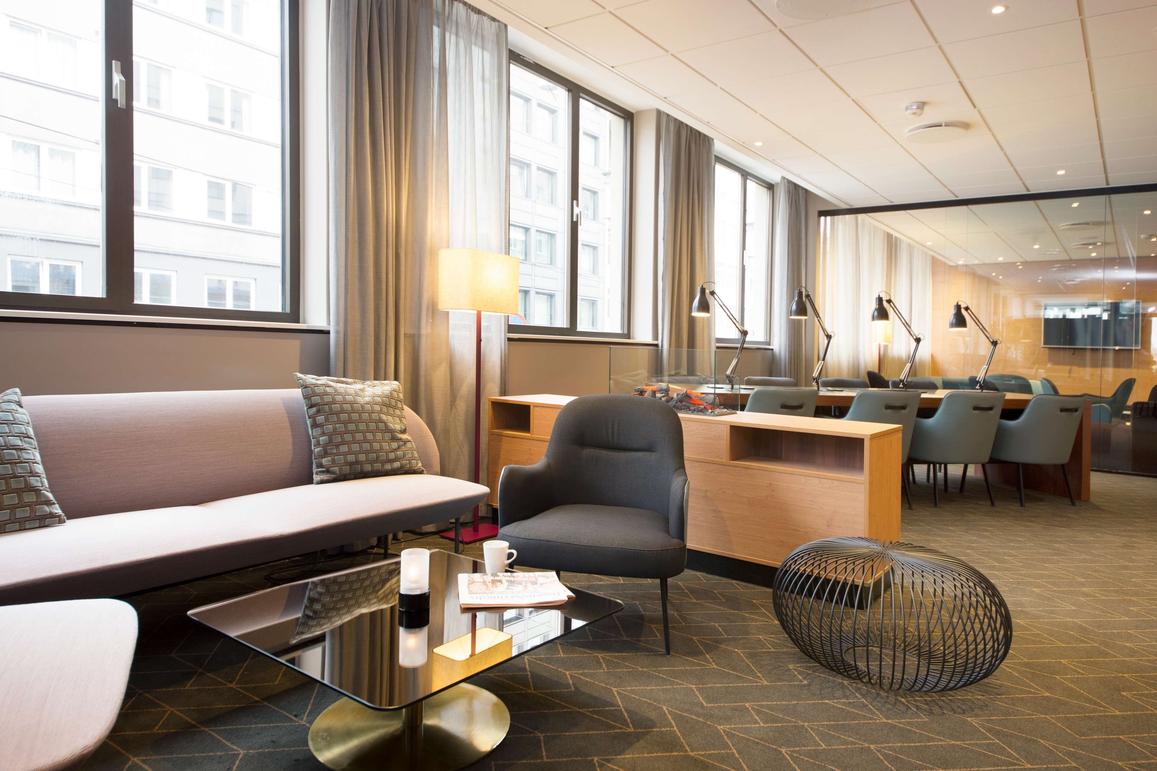 Un moderno vestíbulo de hotel con zona de estar, mostrador de recepción y sala de conferencias.