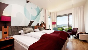 A modern hotel room with a large bed, a desk, and a view of the city. - Scandic Solli Oslo (Oslo)