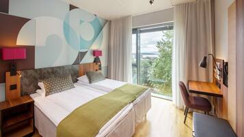 A modern hotel room with a large bed, a desk, and a chair.