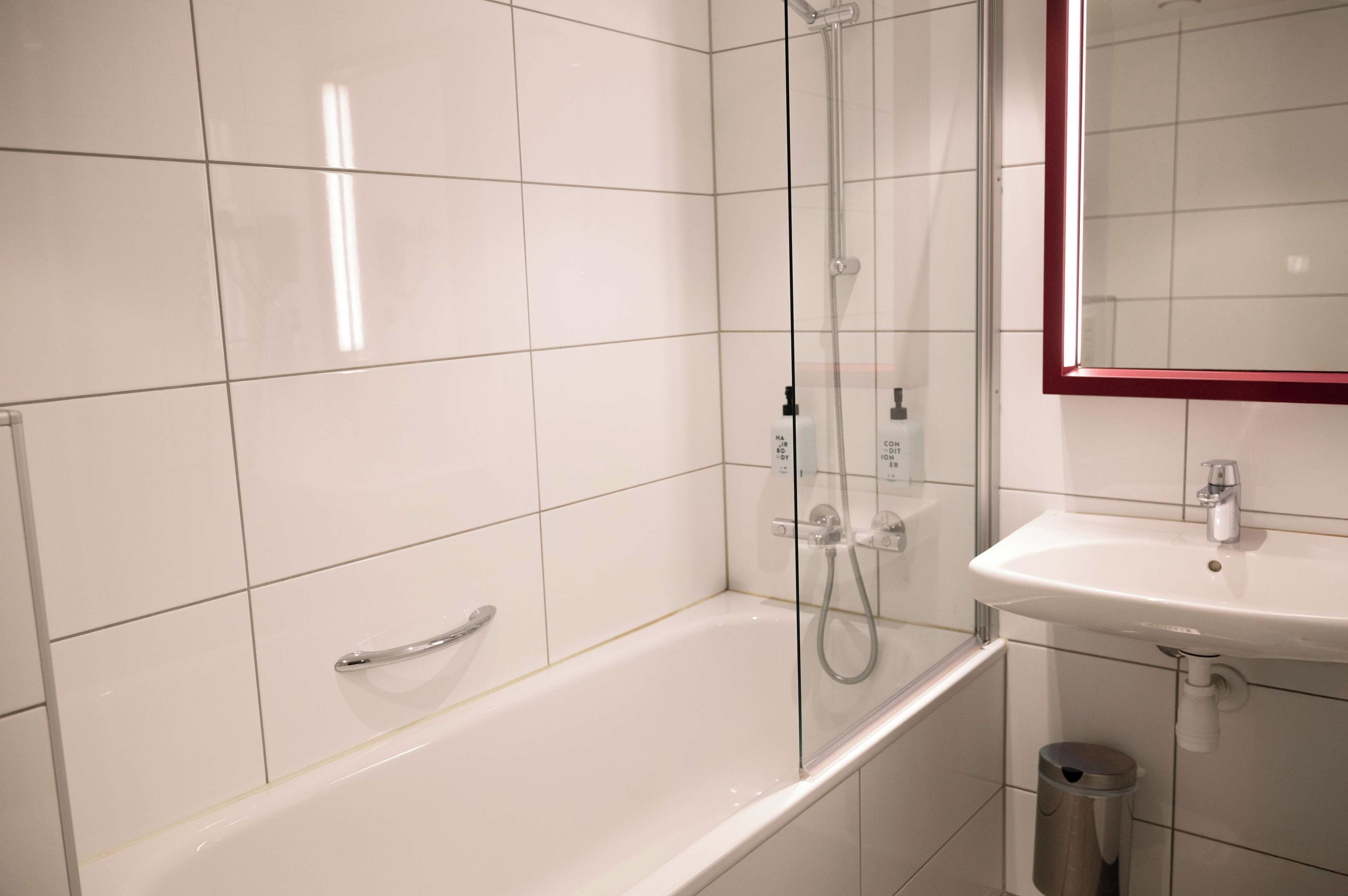 Un baño moderno con bañera, ducha con mampara de vidrio y lavamanos blanco.