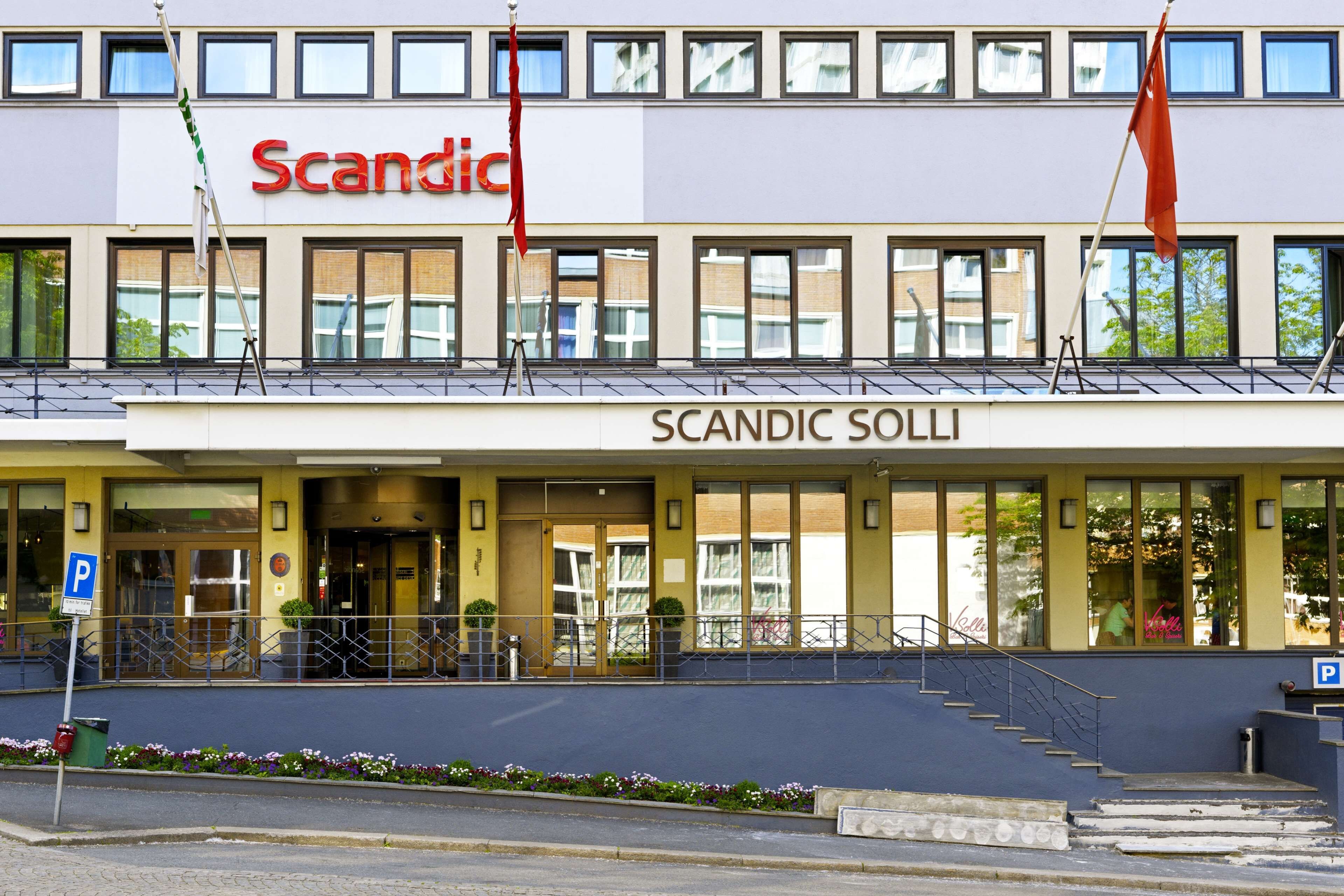 Un hôtel appelé « Scandic », doté d’une façade moderne, de grandes fenêtres et d’une entrée bien visible.