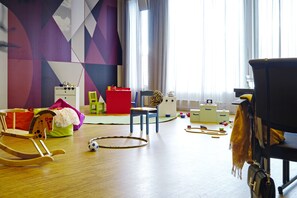 A room with a wooden floor, a rocking chair, a red storage unit, a leopard print chair, and a black chair with a yellow blanket. - Scandic Solli Oslo (Oslo)