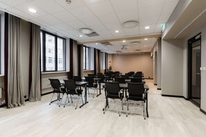A conference room with rows of tables and chairs, large windows, and a neutral color scheme. - Scandic Solli Oslo (Oslo)
