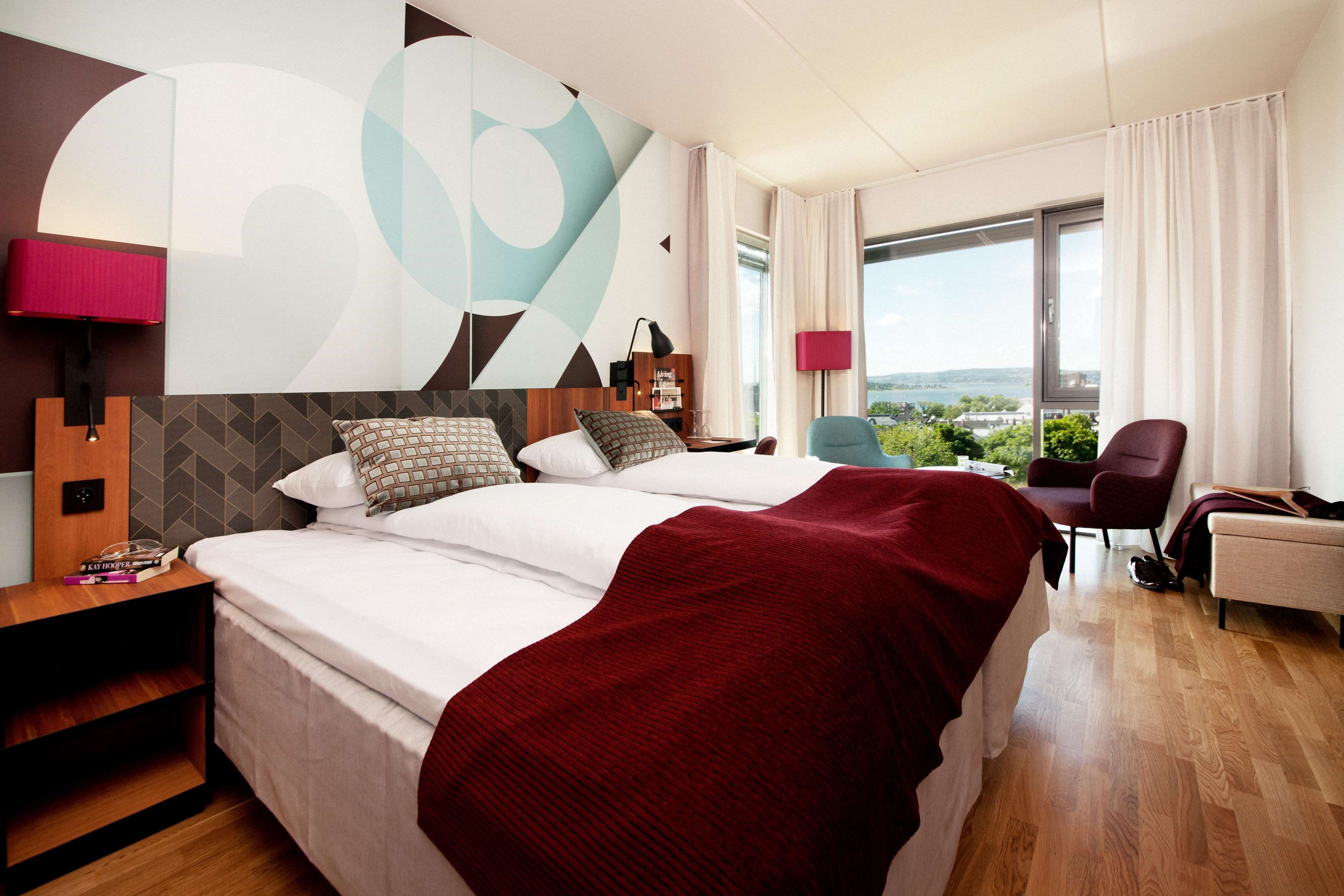 Habitació d'hotel moderna amb un llit gran, escriptori i vista a la ciutat.
