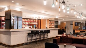 A bar area with a counter, multiple bar stools, and a seating area with a round table and sofas. - Scandic Solli Oslo (Oslo)