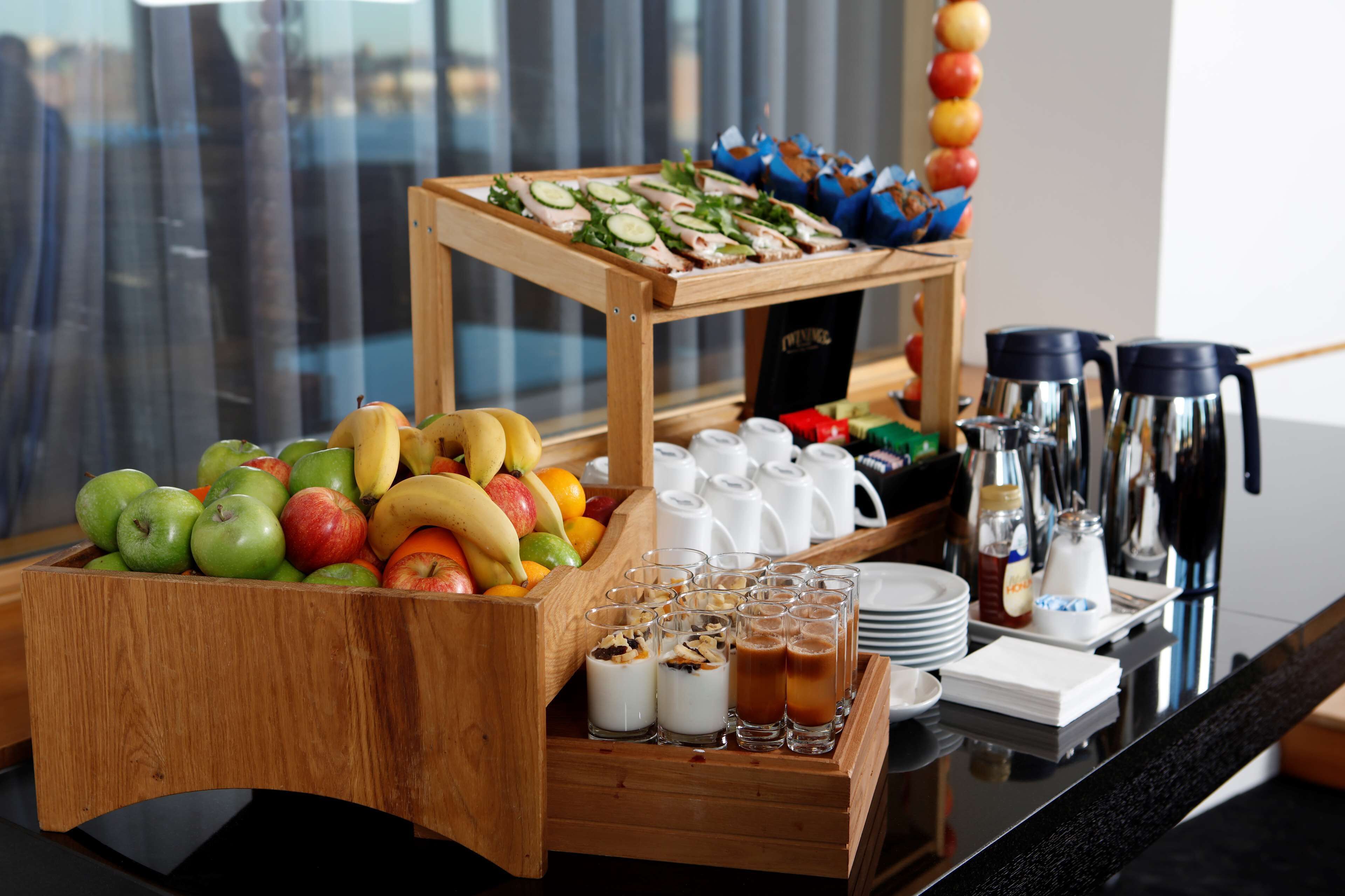 A breakfast buffet with fruits, yogurt parfaits, and coffee options.