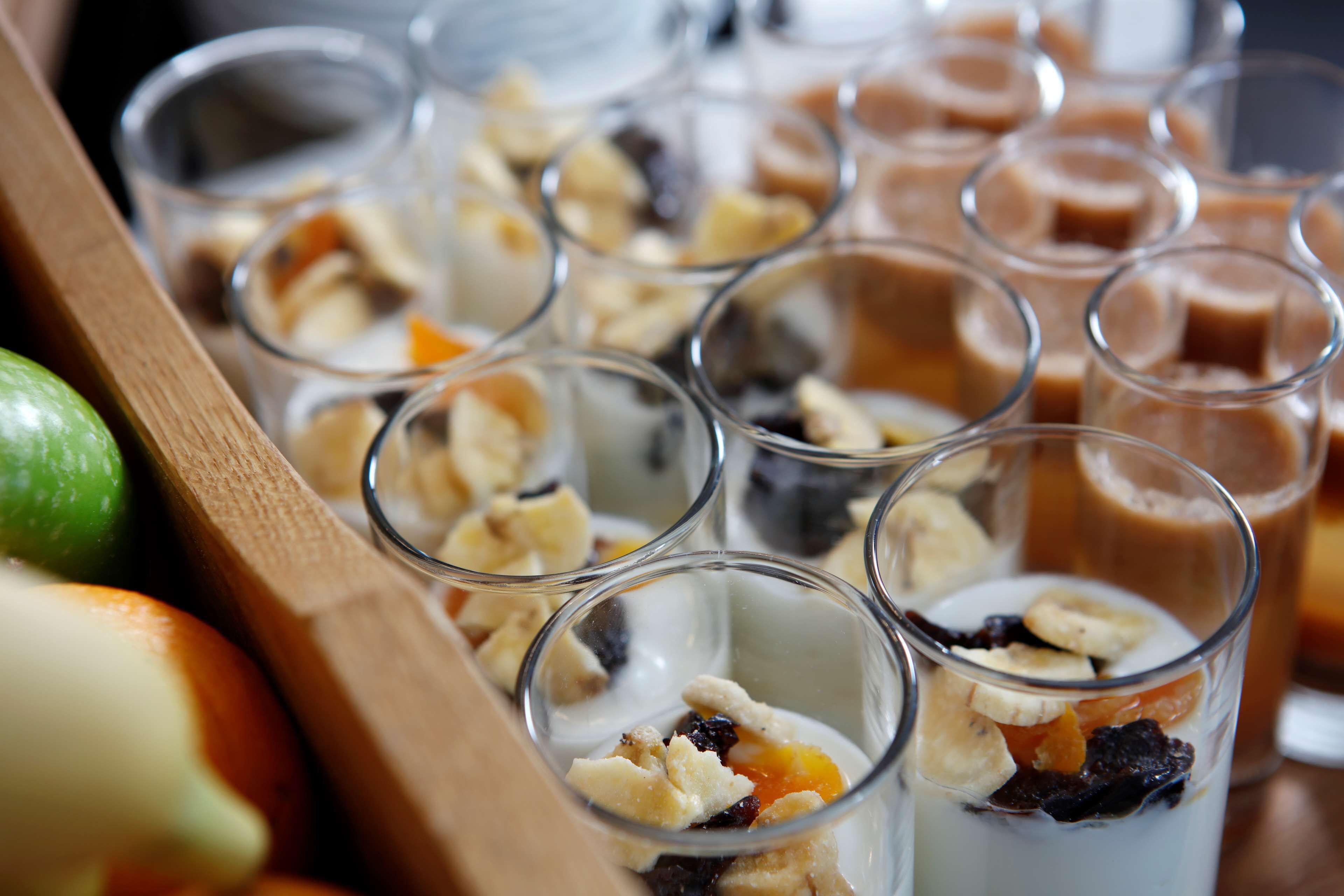A tray of assorted desserts in clear glasses, including fruits and nuts.