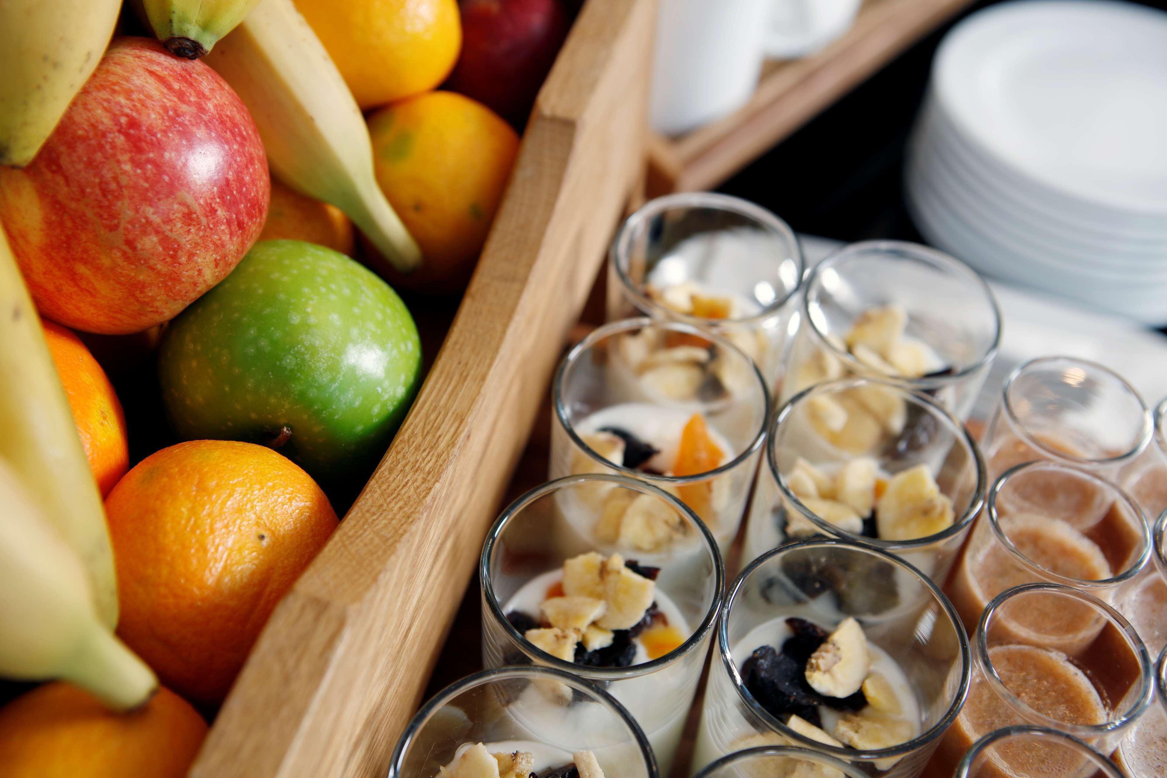 A wooden tray with fruits and glasses of yogurt parfaits.