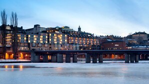 A hotel with multiple floors, a bridge, and a frozen river in the foreground. - Hilton Stockholm Slussen (Stockholm)