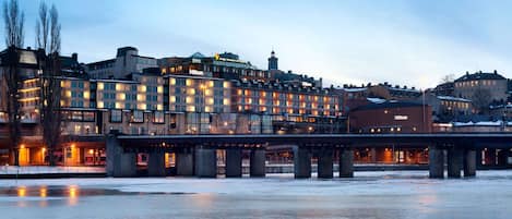 A hotel with multiple floors, a bridge, and a frozen river in the foreground.