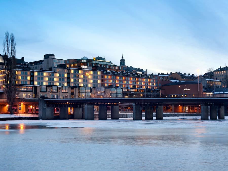 Un hotel de varios pisos, un puente y un río congelado al frente.
